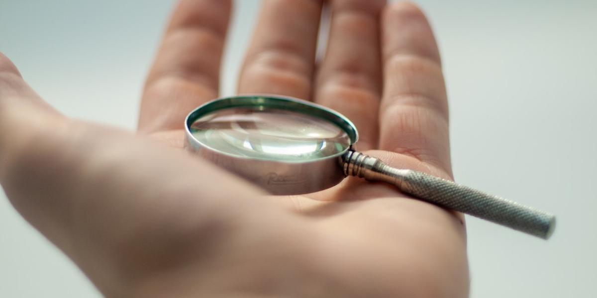 A hand holding magnifying glass