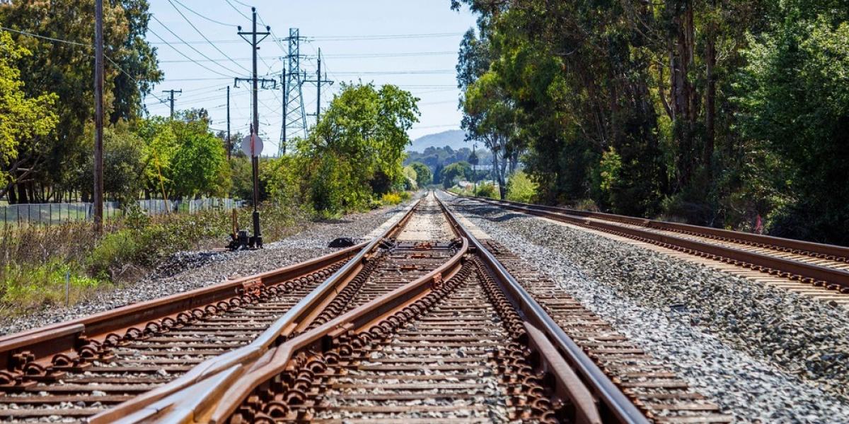 Two train tracks merging into one. The track continues to the horizon.