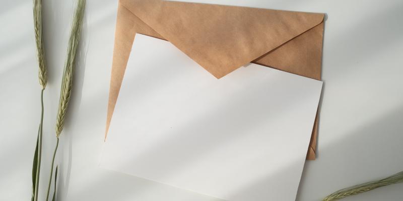 Ett brunt kuvert, ett vitt kort och sädesax