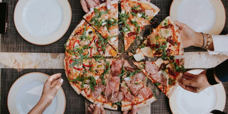 Ihmisiä jakamassa pitsaa.